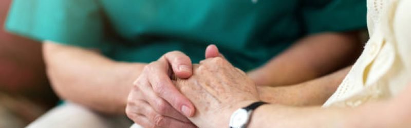 Nurse consoling her elderly patient by holding her hands
